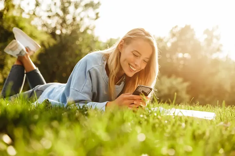 woman in the grass looking at phone
