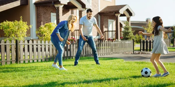 family kicking soccer ball together in backyard